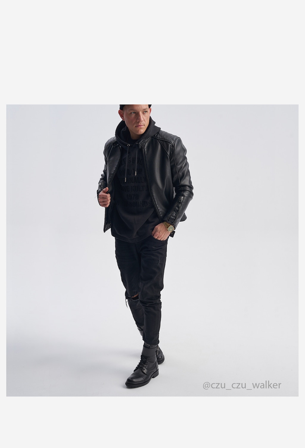 Stylowy mężczyzna w czarnej skórzanej kurtce i spodniach, prezentujący czarne bikery Wojas model 24034-51 ze skóry licowej, idealne do codziennych stylizacji.