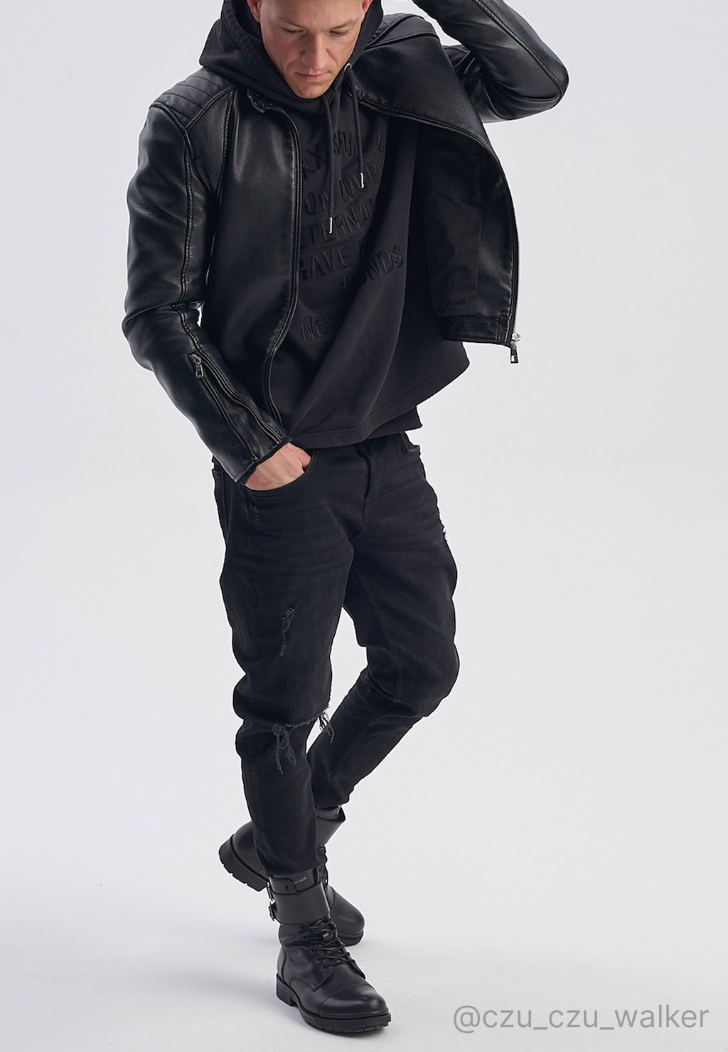 Czarne męskie bikery Wojas 24034-51 za kostkę ze skóry licowej prezentowane przez modela w czarnej stylizacji z kurtką skórzaną i bluzą z kapturem.