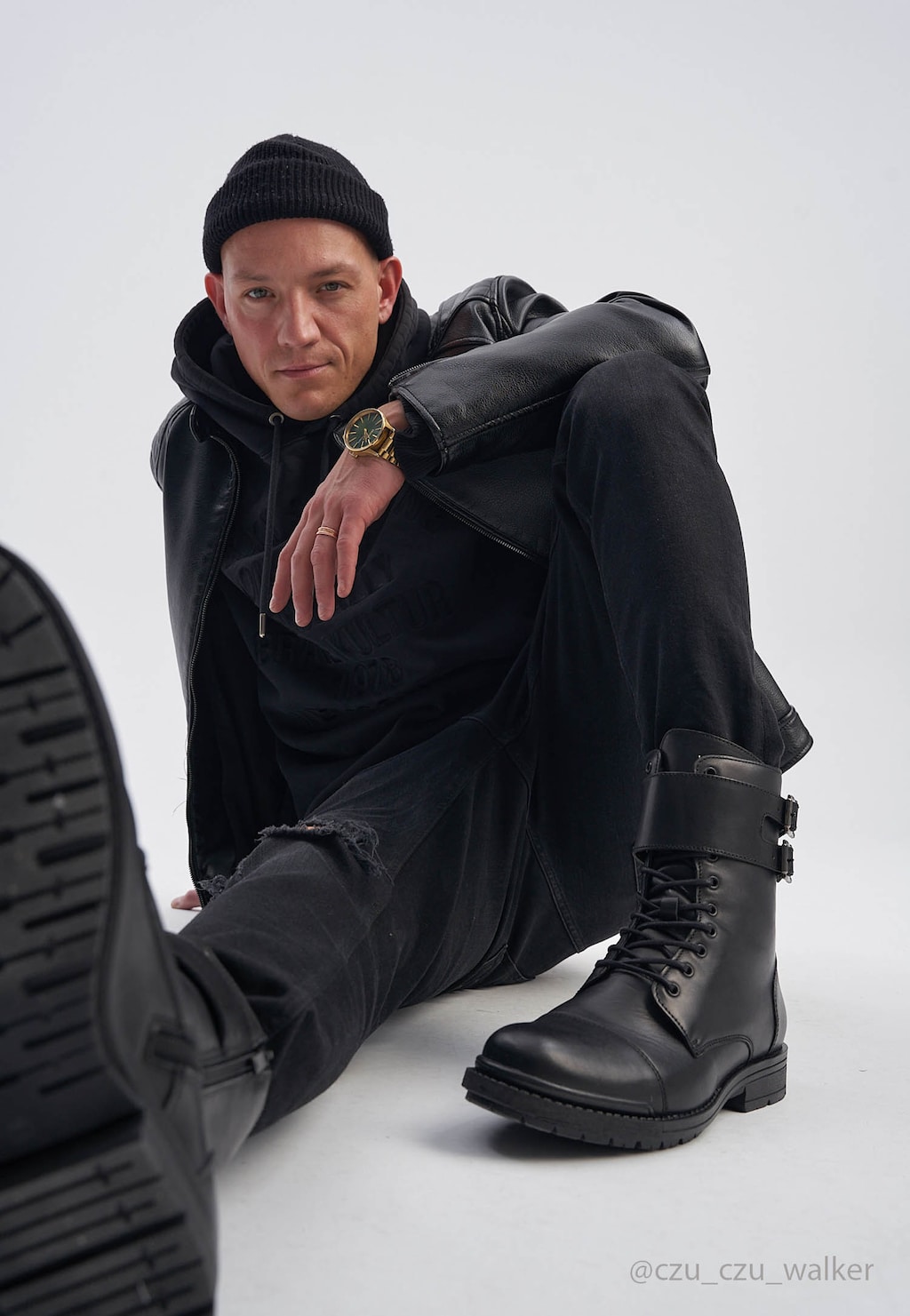 Czarne męskie bikery Wojas 24034-51 ze skóry licowej prezentowane na modelu w ciemnej stylizacji, ukazujące elegancki design butów za kostkę z charakterystycznymi klamrami.