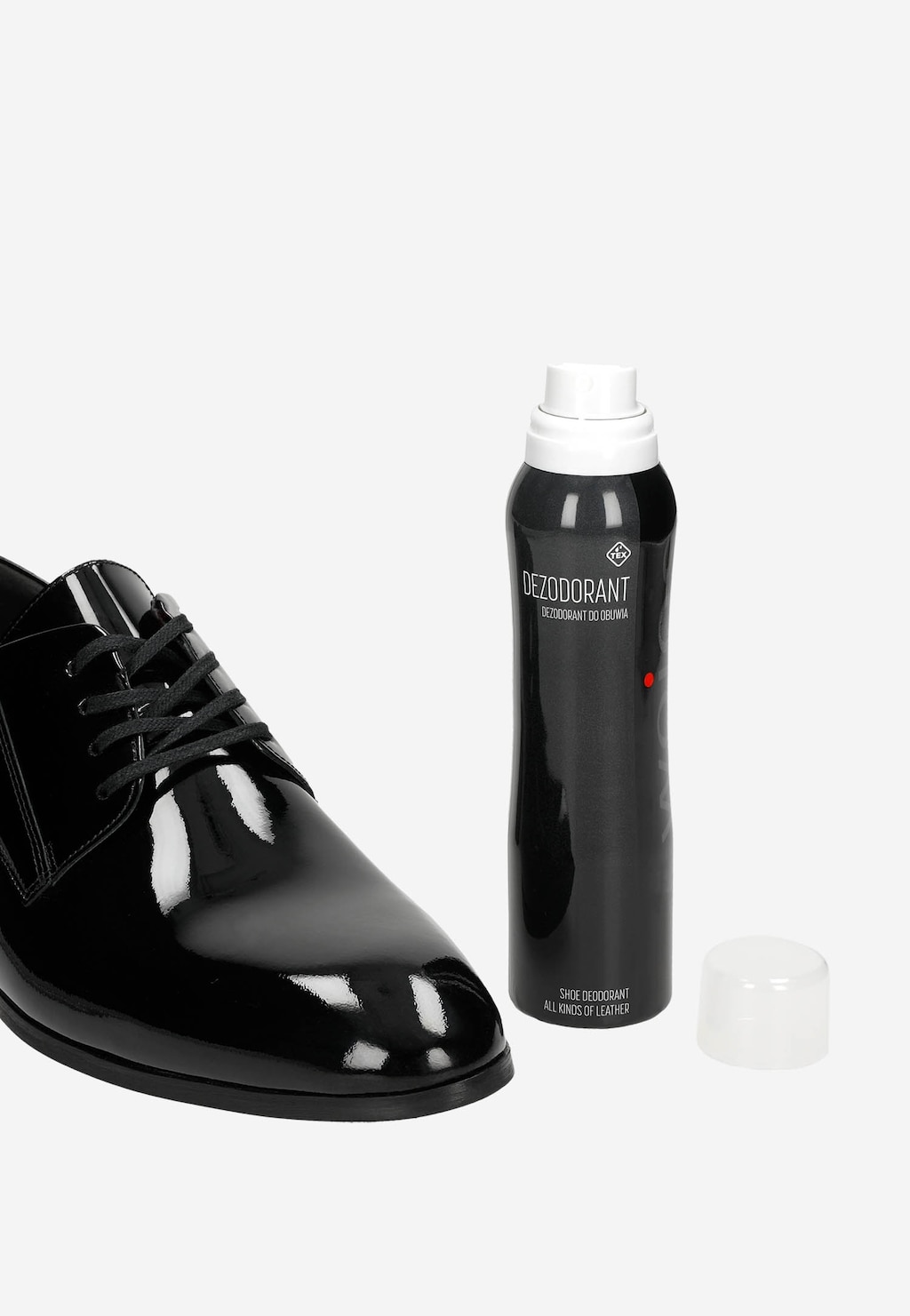Czarny lakierowany but marki Wojas obok dezodorantu w sprayu model 99014-00 o pojemności 150 ml w ciemnym aerozolu z białą nakrętką.