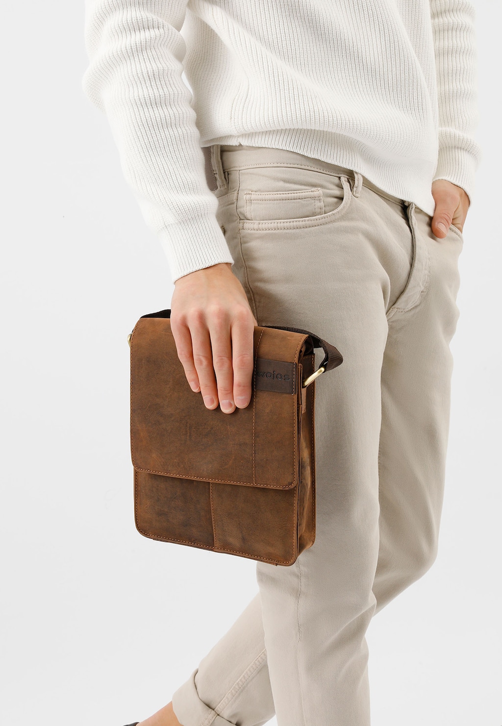 Elegancka brązowa torba męska Wojas model 80043-92 ze skóry crazy horse trzymana w dłoni przez mężczyznę w jasnych spodniach i białym swetrze.