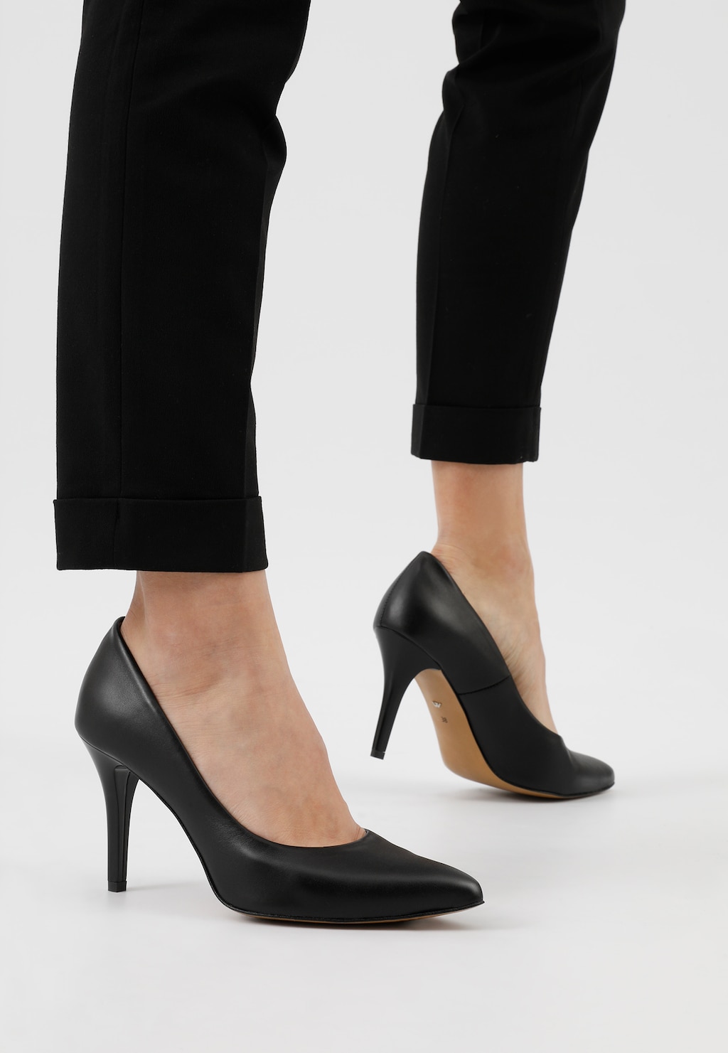 Eleganckie czarne czółenka Wojas model 9275-51 na wysokim obcasie, prezentowane na nodze w czarnych spodniach, ukazane z profilu.