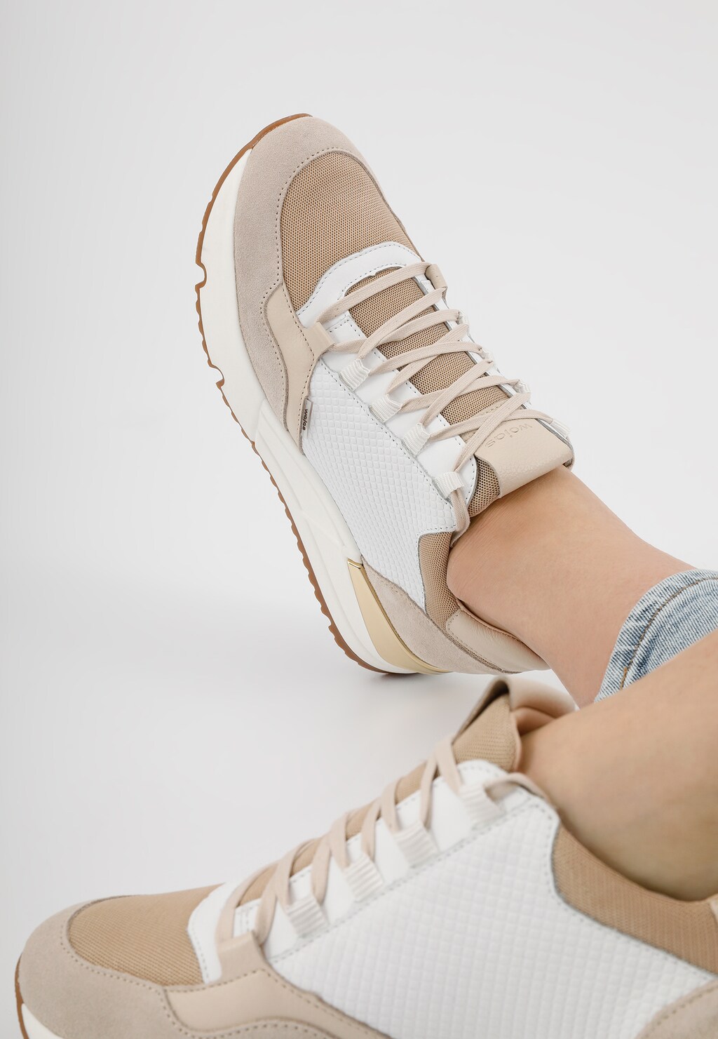 Biało-beżowe sneakersy Wojas model 46137-89 na nodze, ukazane z boku. Sportowe buty damskie ze sznurowaniem i gumową podeszwą, prezentowane w codziennej stylizacji.