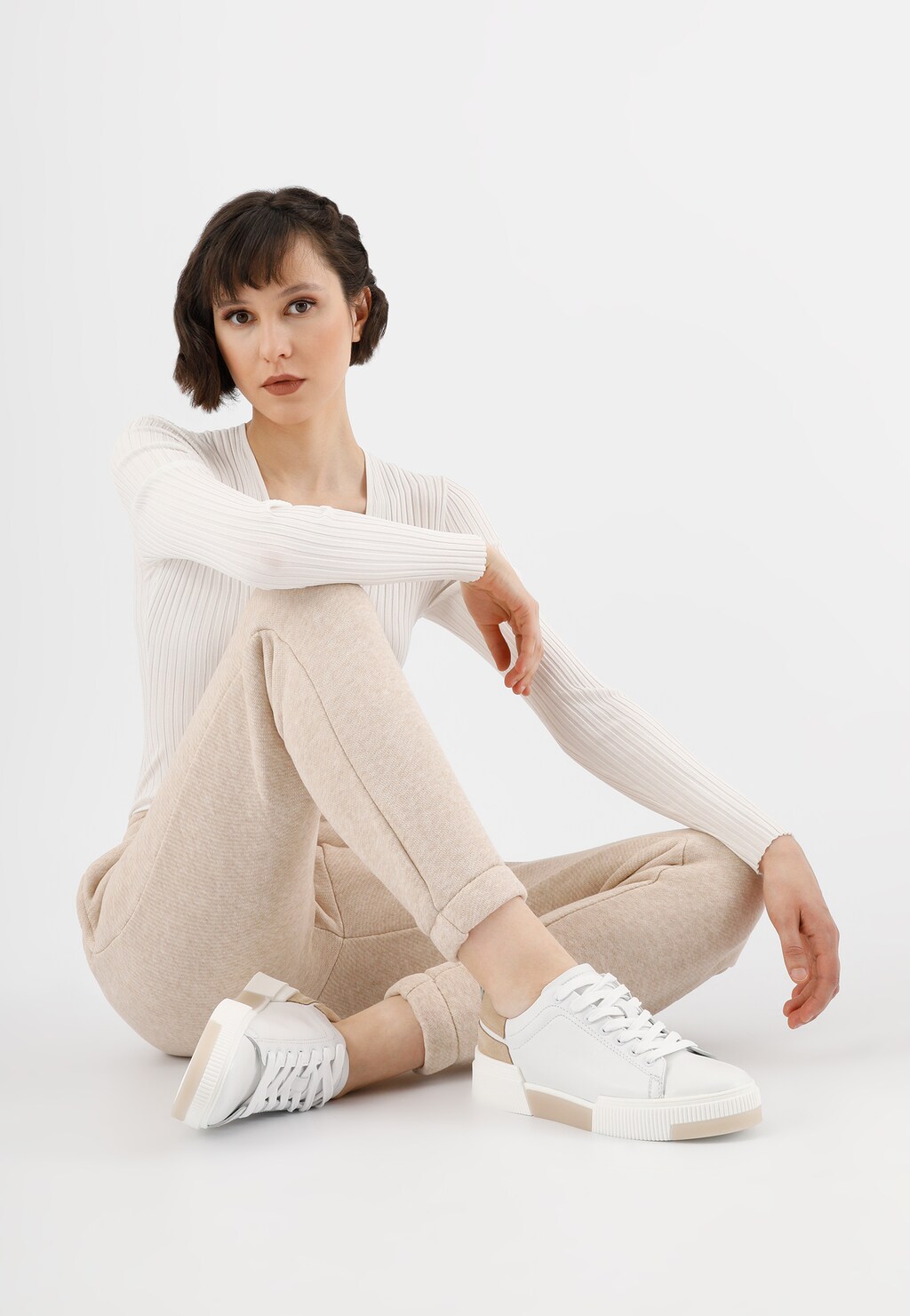 Stylowy outfit z białymi trampkami Wojas model 46121-54 z beżowymi akcentami, idealnie uzupełniający jasny, minimalistyczny strój w beżowych tonacjach.