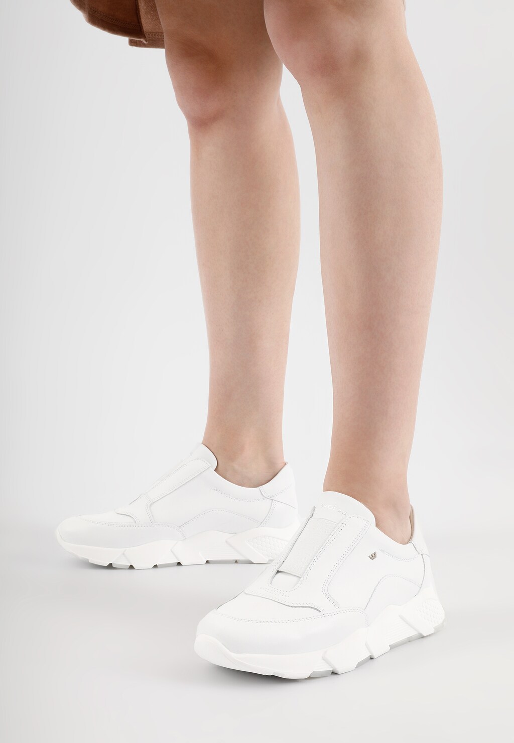 Białe sneakersy wsuwane Wojas model 46119-59 prezentowane na nogach. Buty damskie z grubą podeszwą, sportowy design, widok z boku.