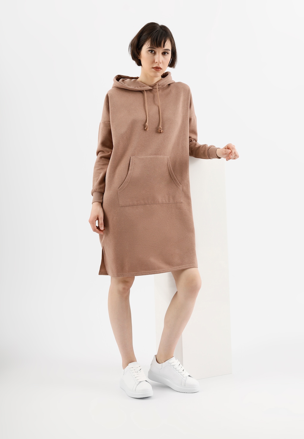 Beżowa sukienka typu hoodie z kieszenią kangurkową, prezentowana z klasycznymi białymi trampkami Wojas model 46020-50 ze skóry licowej.