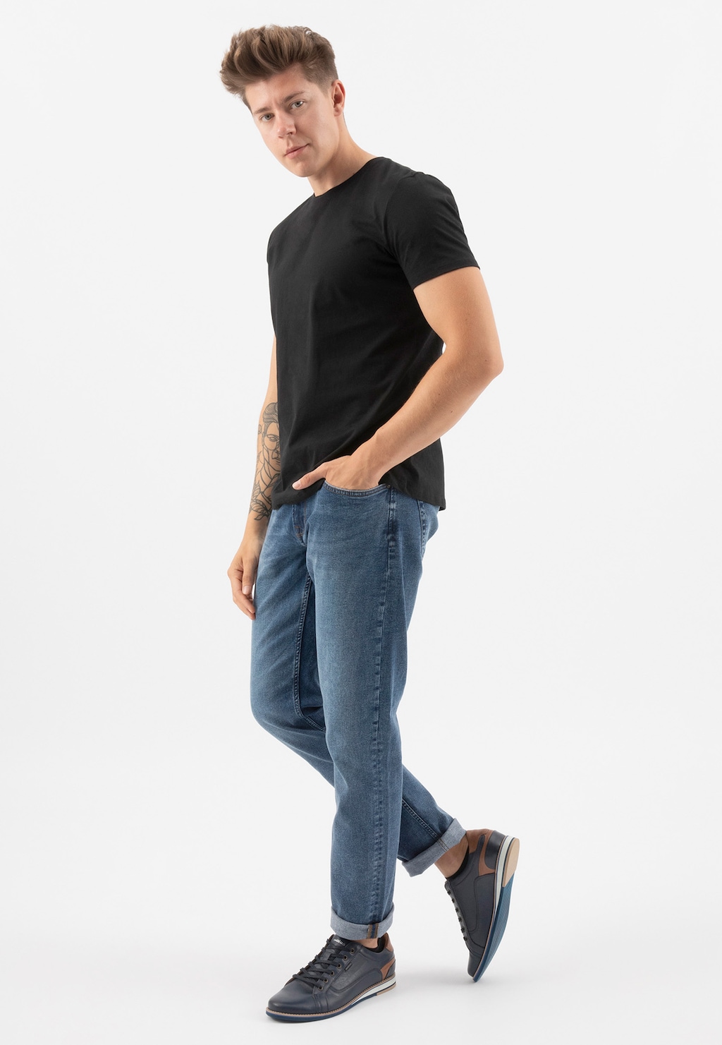 Mężczyzna w czarnym t-shircie i jeansach prezentujący granatowe półbuty męskie Wojas model 10023-56 z brązowymi wstawkami, widoczne na nogach w pełnej okazałości.