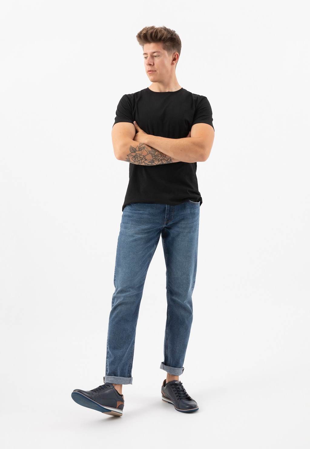 Mężczyzna w czarnym t-shircie i niebieskich jeansach prezentujący granatowe półbuty męskie Wojas model 10023-56 z brązowymi wstawkami.