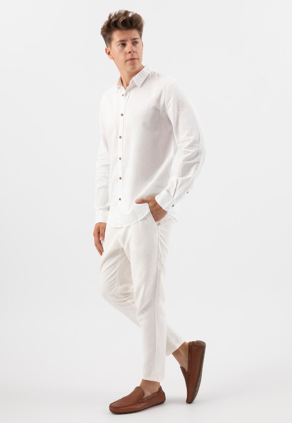 Mężczyzna w białej koszuli i spodniach, prezentujący jasnobrązowe skórzane mokasyny męskie Wojas model 10047-52, widok pełnej sylwetki z profilu.