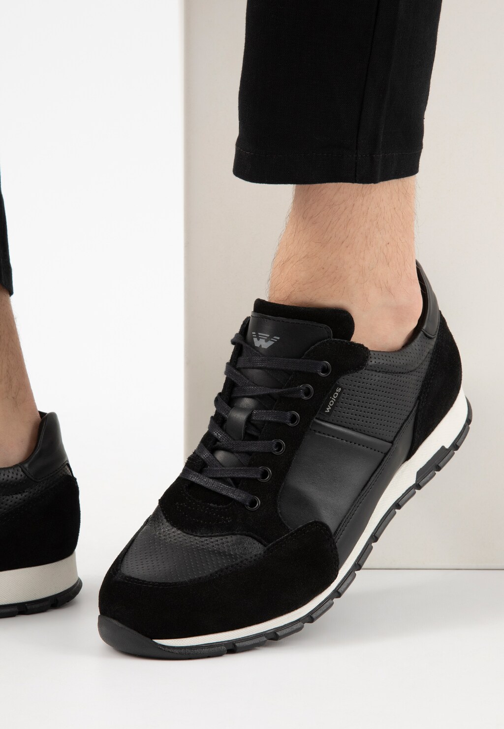 Czarne sneakersy męskie Wojas model 10051-71 z łączonych skór, widoczne na stopie. Buty wyróżniają się kontrastującą białą podeszwą i eleganckim designem łączącym różne faktury skóry.