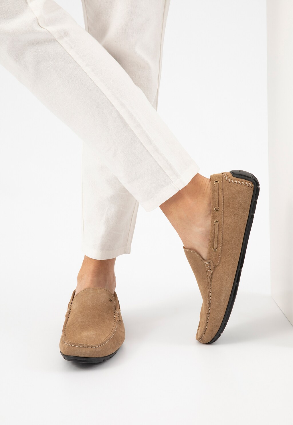 Beżowe mokasyny męskie Wojas model 10047-64 wykonane z dwoiny welurowej, pokazane na stopie w białych spodniach, widok boczny podkreślający klasyczny, wygodny fason.