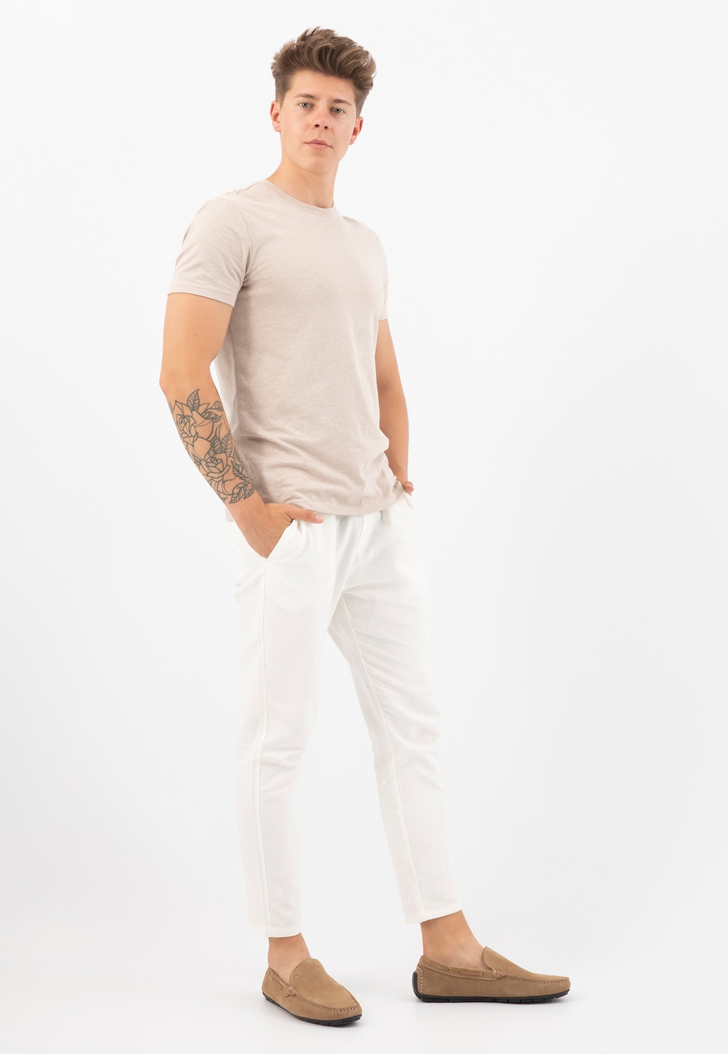 Beżowe mokasyny męskie Wojas model 10047-64 z dwoiny welurowej prezentowane na modelce w beżowej koszulce i białych spodniach, widok z boku pokazujący elegancki profil obuwia.