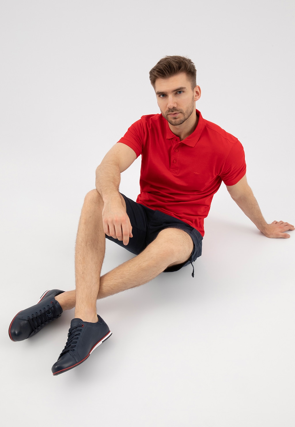 Granatowe półbuty męskie Wojas model 8071-56 z czerwonym akcentem na podeszwie, prezentowane przez osobę w czerwonej koszulce polo i czarnych szortach.