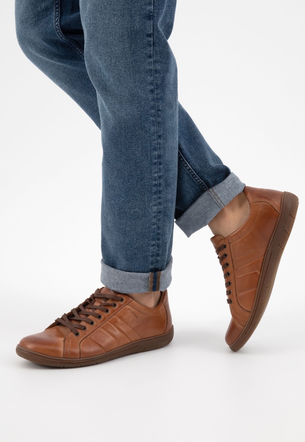 Jasnobrązowe półbuty męskie Wojas 9080-53 ze skóry z ozdobnymi przeszyciami, prezentowane na nodze w podwiniętych jeansach, widok z boku.