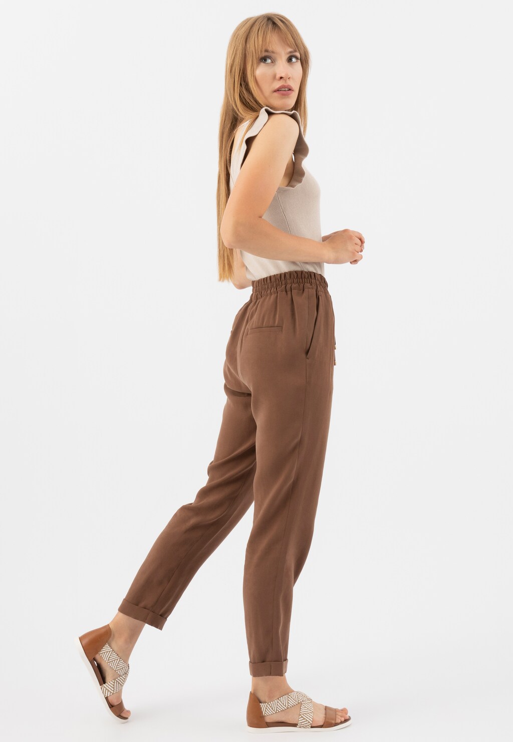 Elegancki zestaw z beżowym topem i brązowymi spodniami, uzupełniony jasnobrązowymi sandałami Wojas model 76018-83 z plecionymi paskami - idealne na letnie stylizacje.