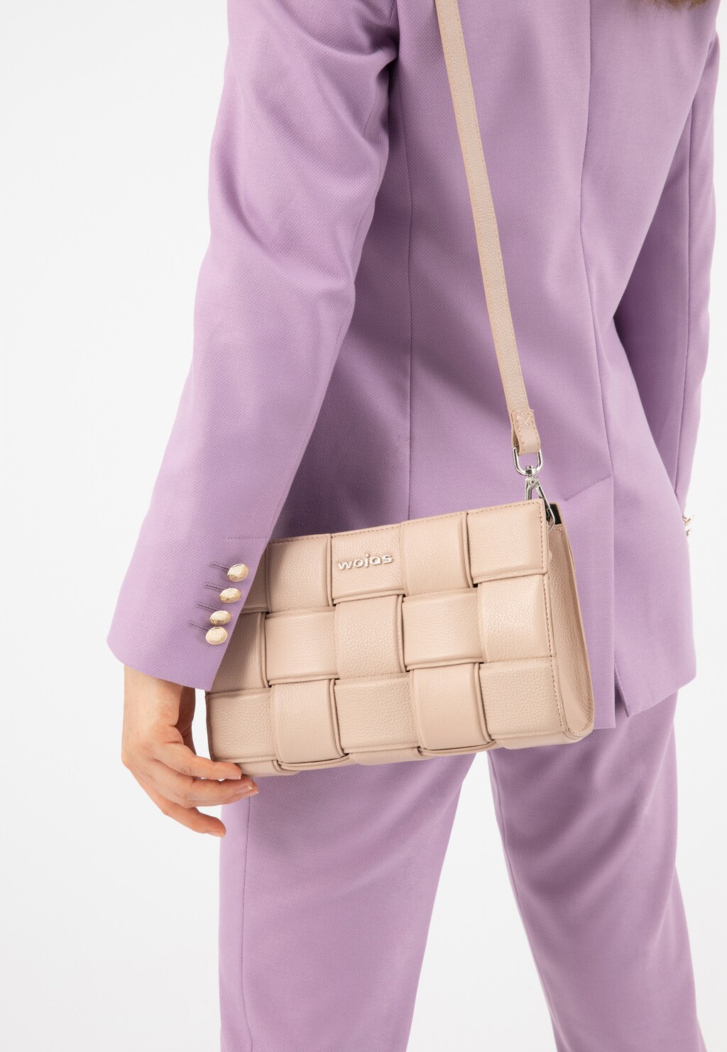Beżowa torebka damska Wojas model 80235-54 z plecioną strukturą skóry licowej, zawieszona na pasku przez ramię, prezentowana na tle fioletowego garnituru.