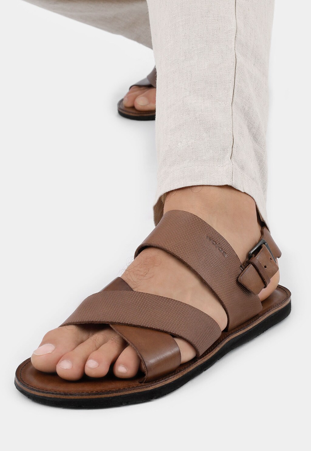 Brązowe sandały męskie Wojas model 29007-52 z przeplatanymi paskami na stopie, prezentowane na nodze w jasnych spodniach, widok z boku.