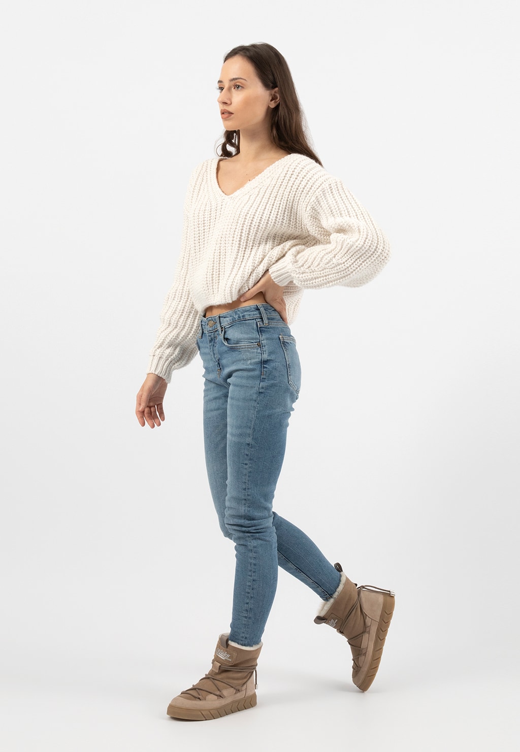 Modelka w beżowym sweterku i jeansach prezentująca beżowe śniegowce Relaks R55103-74 ocieplane skórą owczą, widok z boku podczas chodzenia.