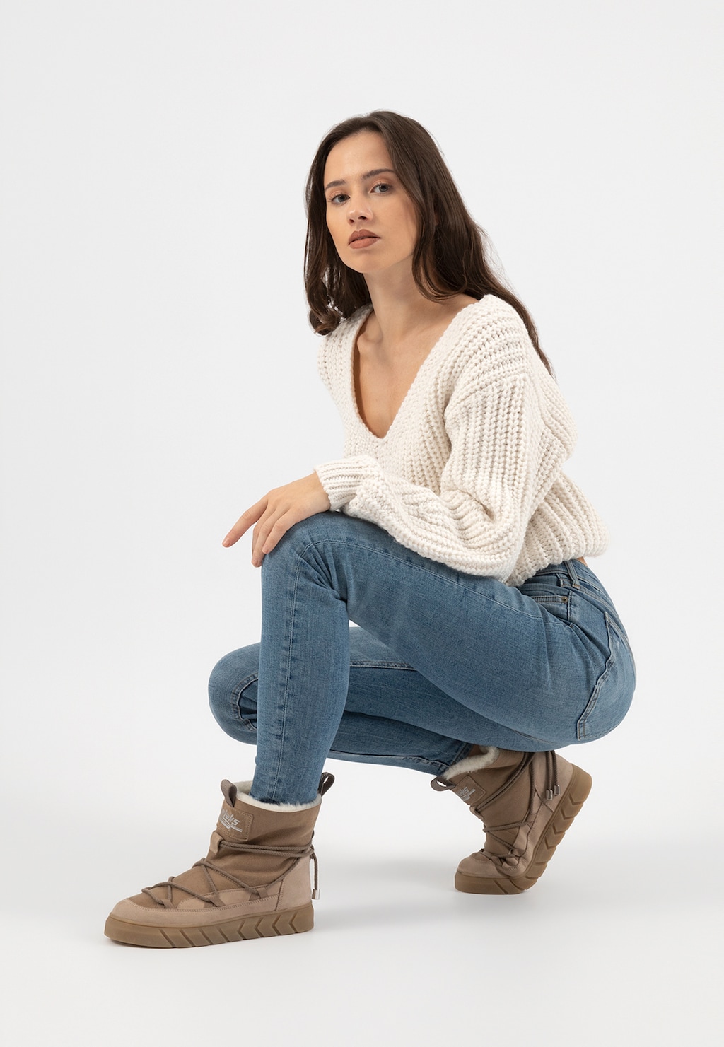 Beżowe śniegowce Relaks R55103-74 ocieplane skórą owczą prezentowane przez modelkę w kucki, ubraną w biały sweter i niebieskie jeansy.