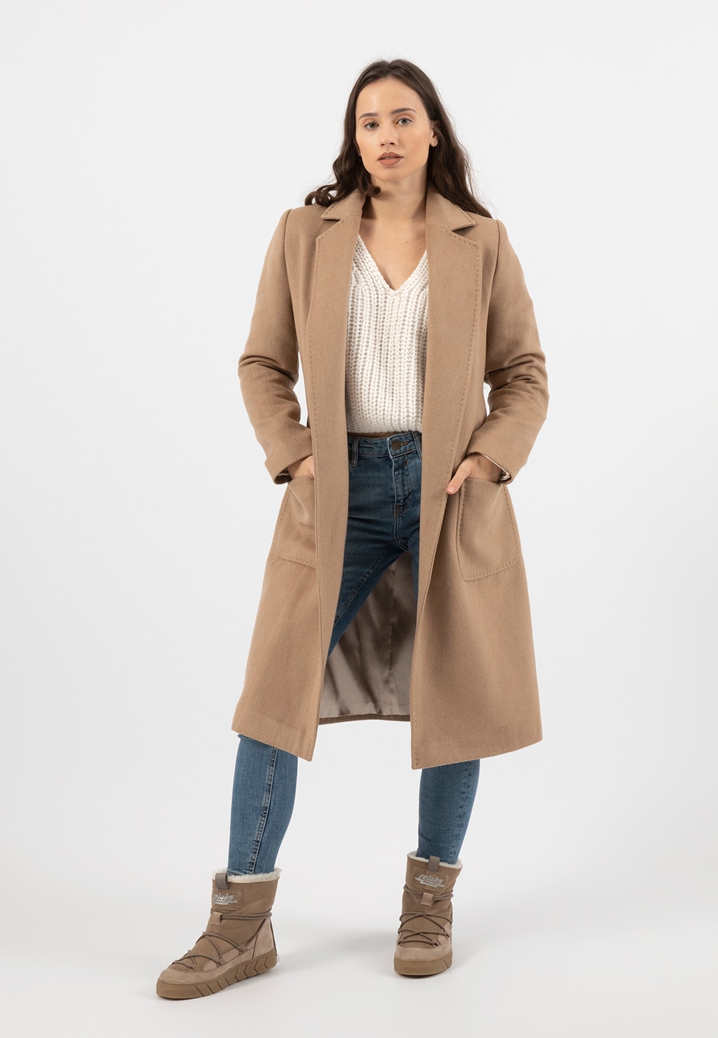 Modelka w beżowym płaszczu i dżinsach prezentuje beżowe śniegowce Relaks R55103-74 ocieplane skórą owczą, idealne na zimowe dni.