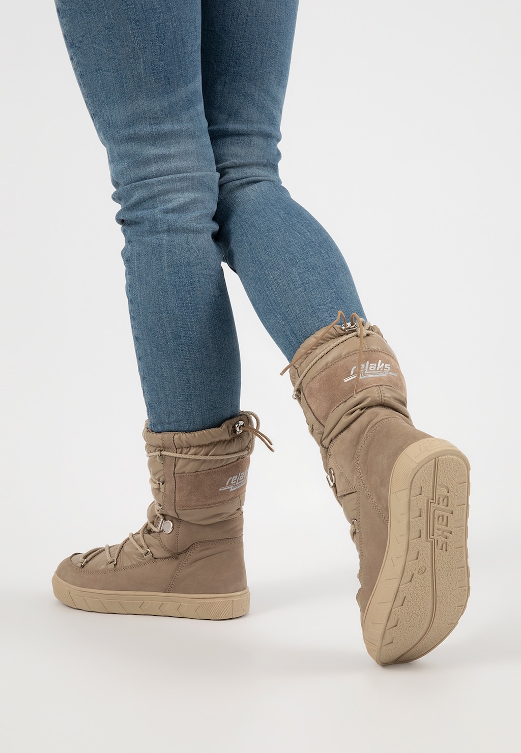 Beżowe wysokie śniegowce damskie RELAKS model R55121-84 prezentowane na nogach w niebieskich jeansach, ukazujące przód i podeszwę obuwia zimowego.