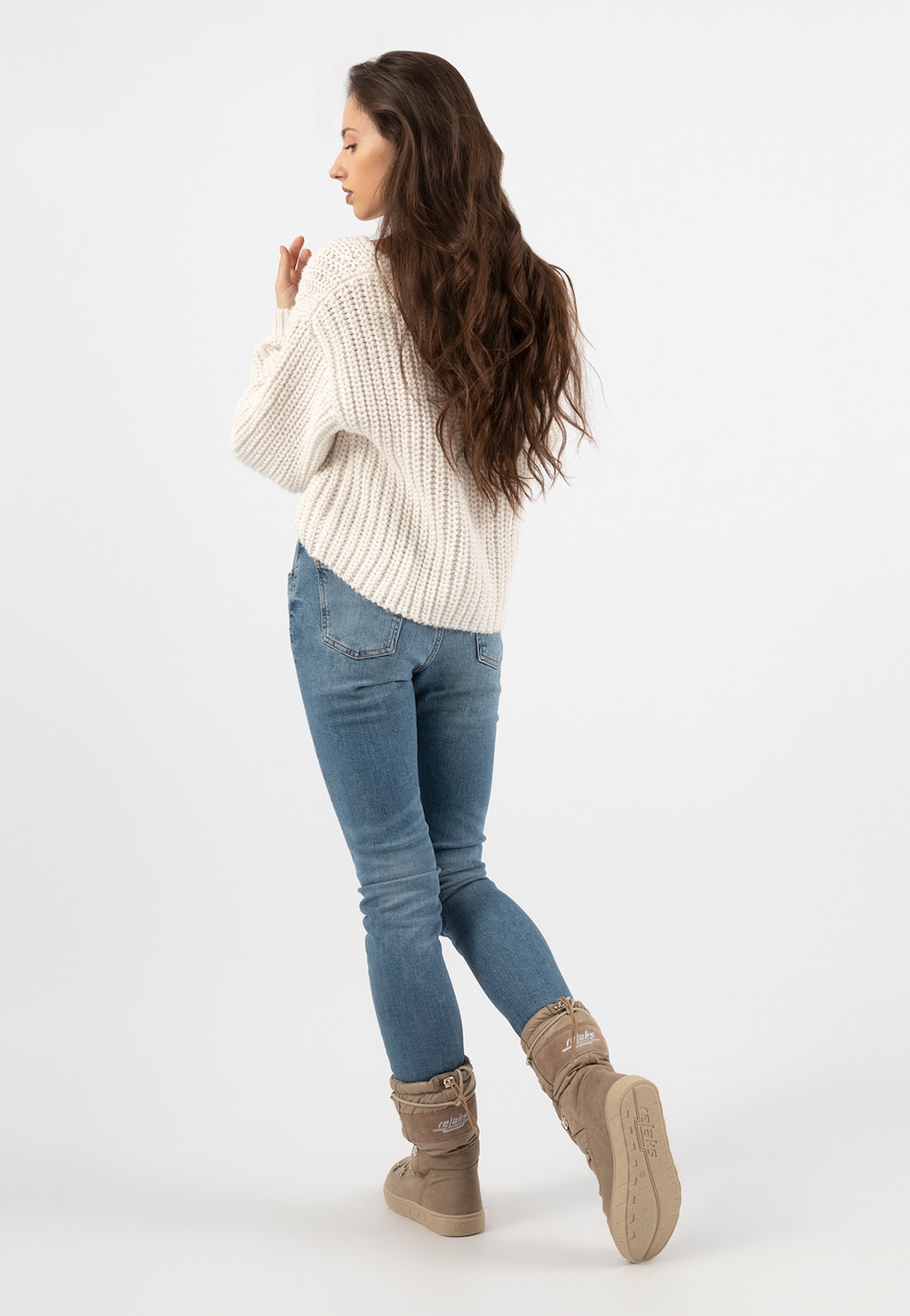Kobieta w białym swetrze i jeansach prezentująca beżowe wysokie śniegowce damskie RELAKS model R55121-84, widok z tyłu ukazujący komfort i styl obuwia.