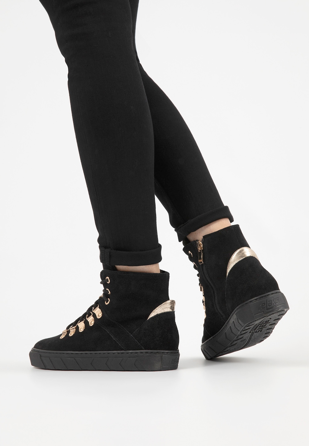 Czarne ocieplane trzewiki damskie Relaks R64006-61 ze złotymi akcentami na podeszwie i sznurowaniu, prezentowane na nogach w czarnych spodniach.