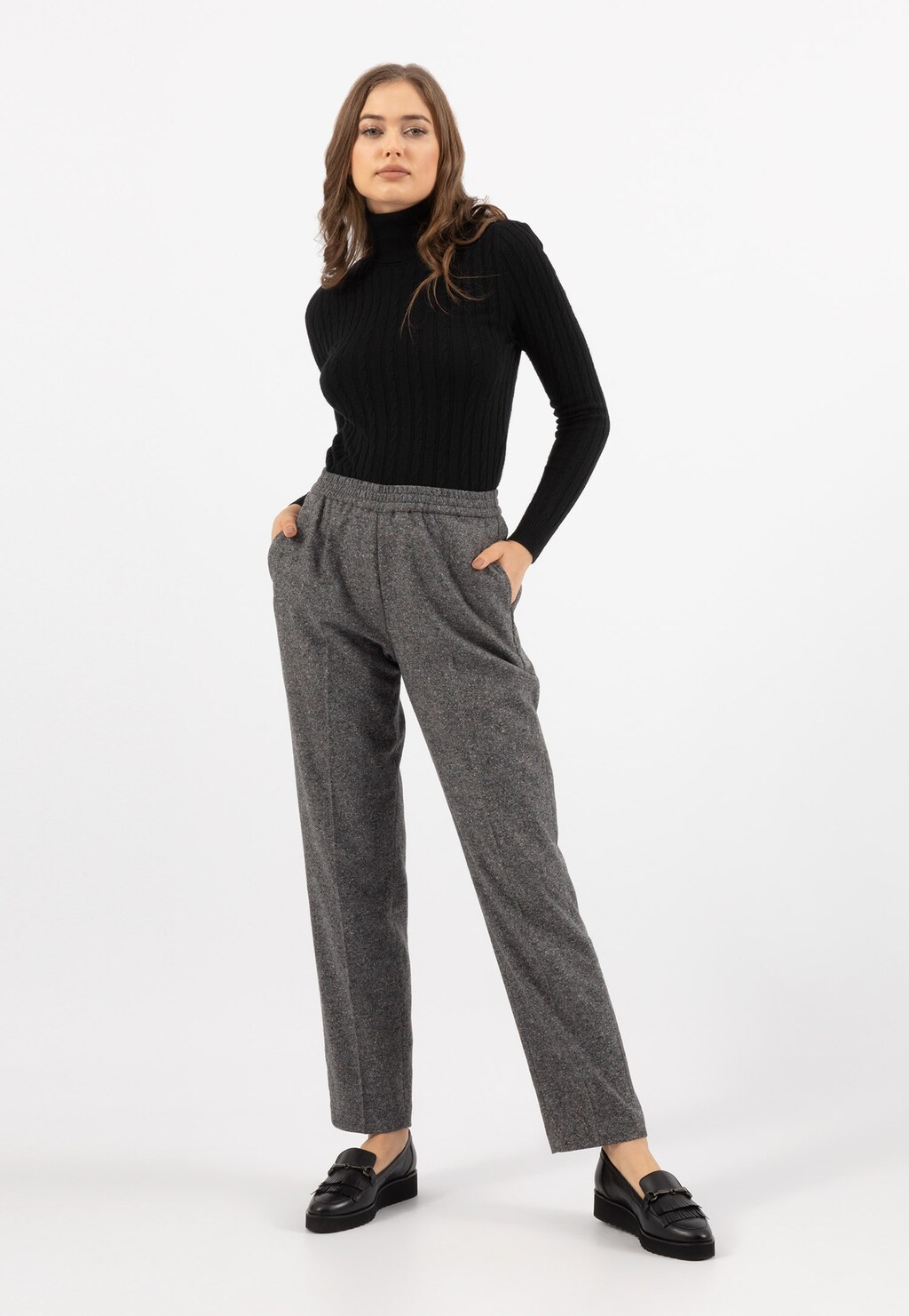 Elegancka stylizacja z czarnymi mokasynami damskimi Wojas 46100-51 z ozdobnymi frędzlami, zestawiona z czarnym golfem i szarymi spodniami.