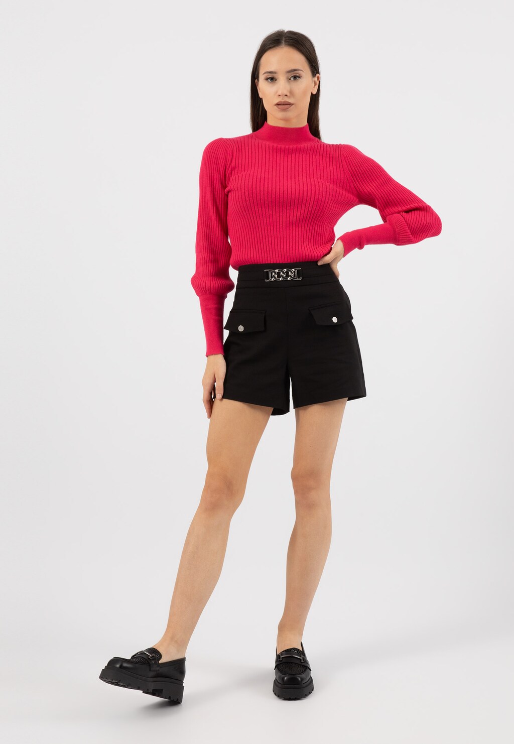 Modelka w różowym prążkowanym swetrze i czarnych szortach, prezentująca czarne damskie mokasyny Wojas model 46188-71 z ozdobnym motywem w cętki i detalem horsebit.