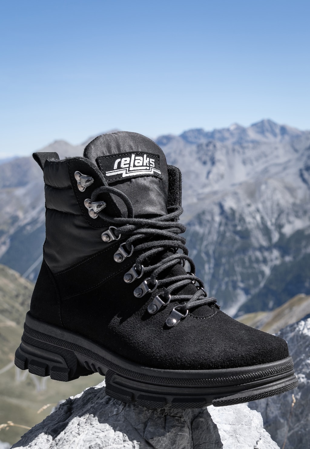 Czarny trzewik damski RELAKS R64005-11 wykonany ze skóry i ortalionu, ukazany na tle górskiego krajobrazu, z grubą podeszwą i systemem sznurowania idealnym na górskie wędrówki.