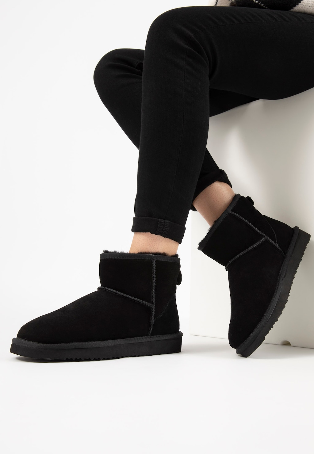 Czarne, ciepłe śniegowce damskie Relaks model R55003-61 z futrzanym wykończeniem, widoczne na nogach osoby w czarnych spodniach. Idealne buty zimowe o krótkim fasonie.
