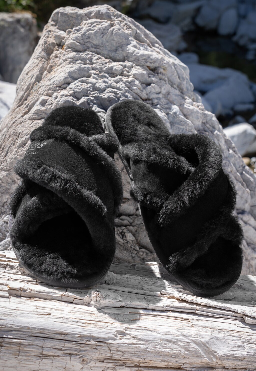 Czarne puchate kapcie damskie RELAKS model R34005-61 z miękkim futrzanym wykończeniem, prezentowane na kamiennym podłożu w naturalnym świetle.