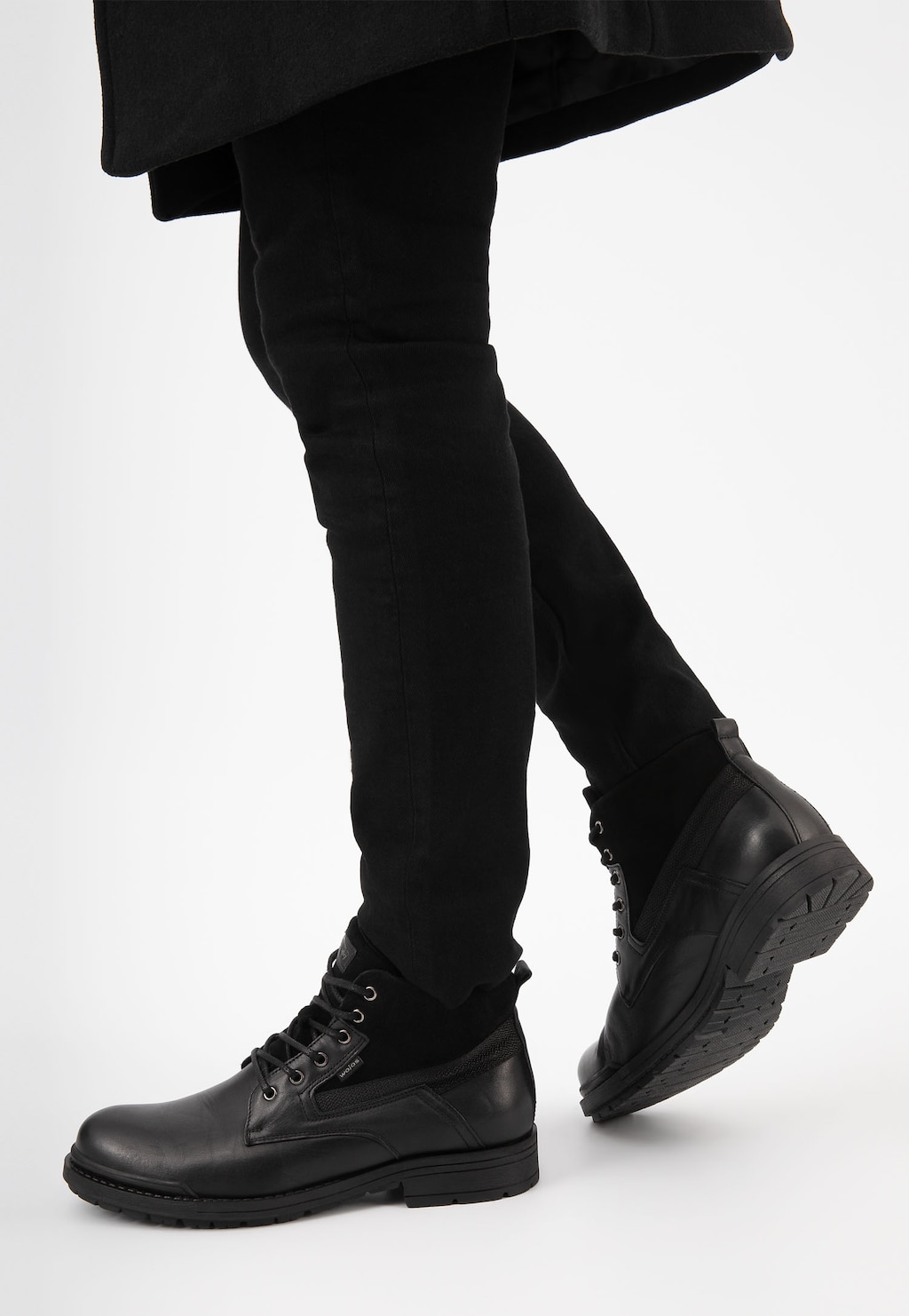 Czarne ocieplane trzewiki męskie Wojas model 24033-71 typu workery, prezentowane na nodze w ciemnych spodniach. Widok z boku ukazuje masywną podeszwę i sznurowany przód.
