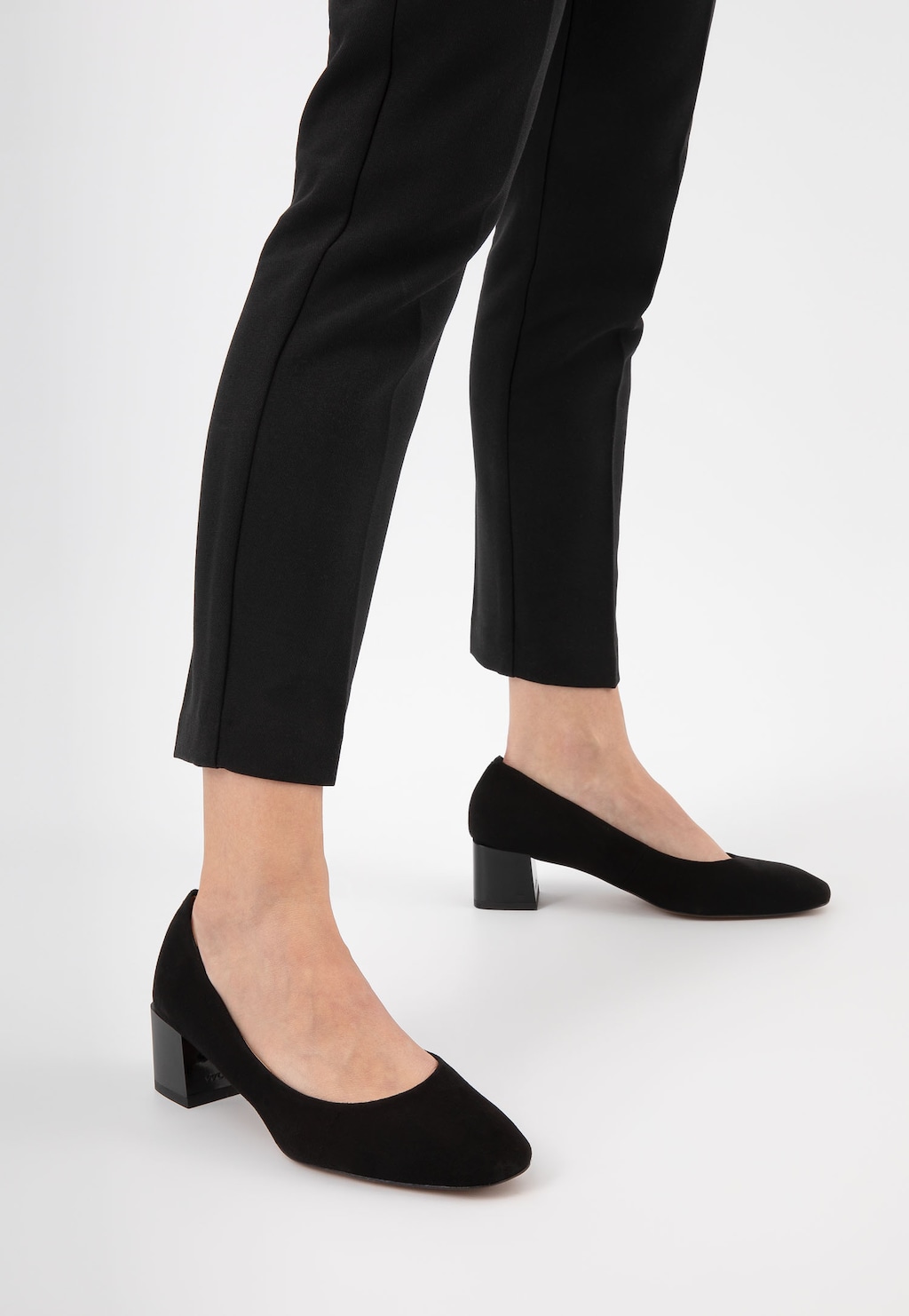 Eleganckie czarne czółenka Wojas 35062-61 z weluru na niewielkim obcasie, prezentowane na nodze modelki w czarnych spodniach, idealne do stylizacji biznesowych.