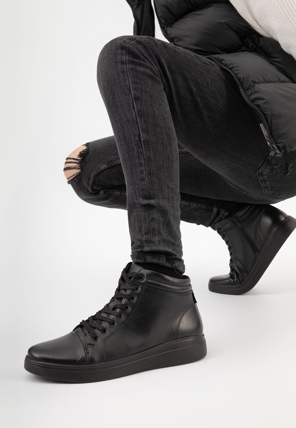 Czarne trampki męskie Wojas model 24025-51 z zamkiem, prezentowane na nodze osoby w ciemnych jeansach z przetarciem, pokazujące stylowy miejski look.
