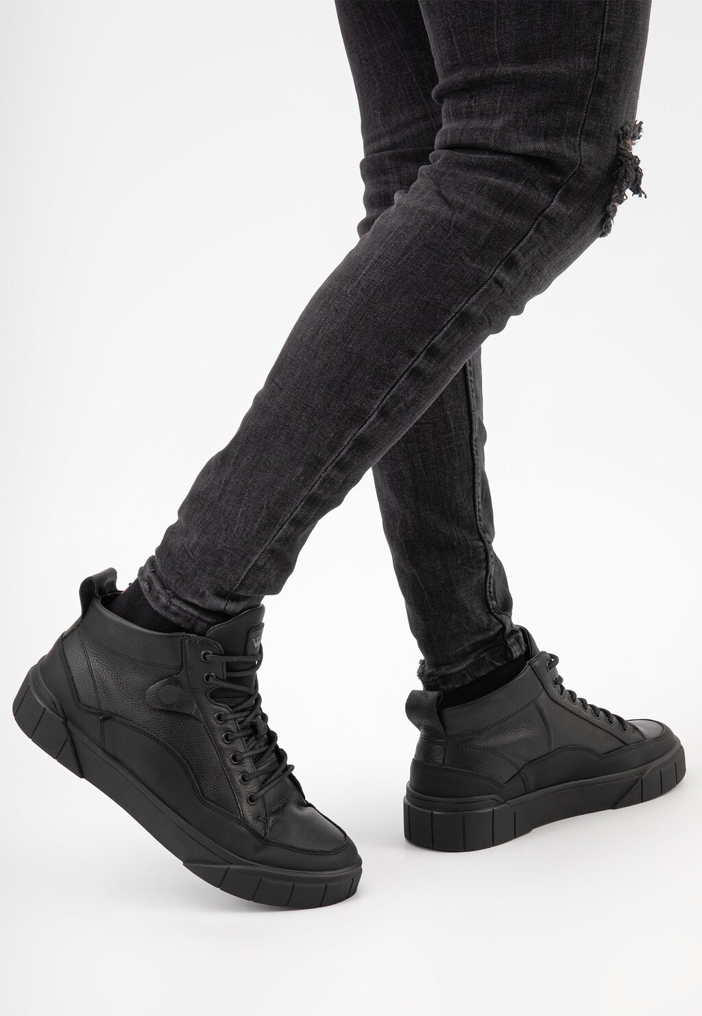 Czarne skórzane trzewiki męskie Wojas 24067-71 w stylu trampek z ociepleniem, prezentowane na nogach osoby w ciemnych jeansach, widok z boku.