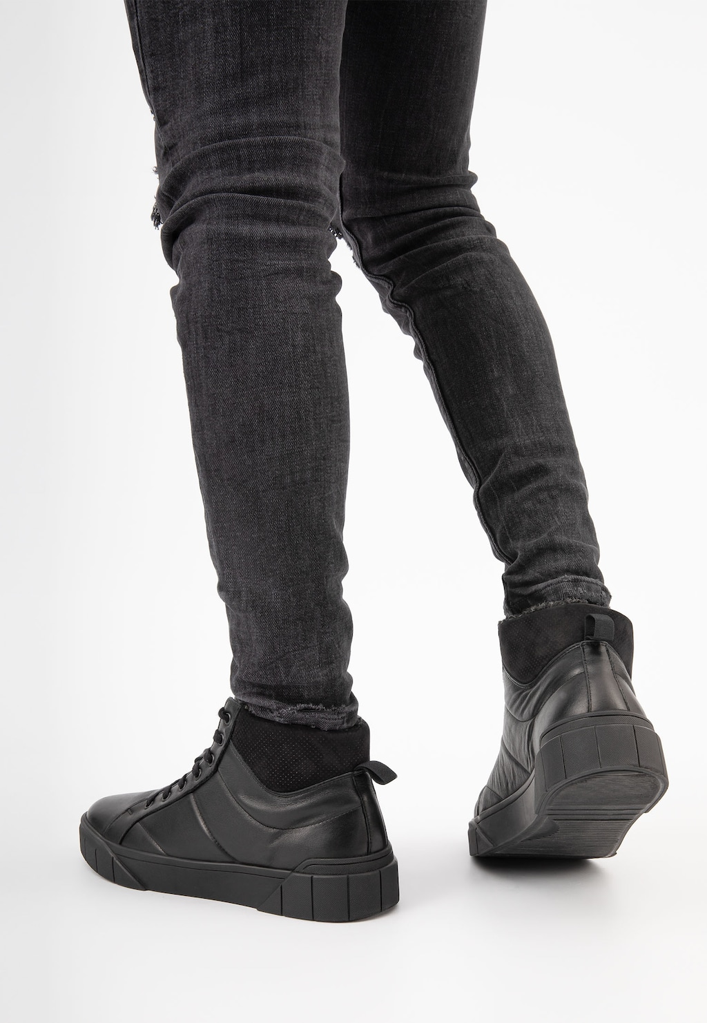 Czarne wysokie trampki męskie Wojas model 24070-71 prezentowane na nogach osoby w ciemnych jeansach, widok z tyłu ukazujący sportowy design obuwia.