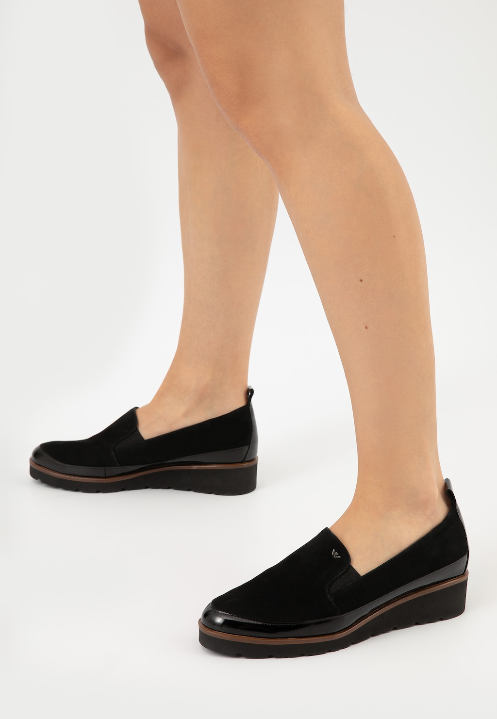 Czarne wsuwane półbuty damskie Wojas model 46008-71 wykonane z łączonych skór, na płaskiej podeszwie, prezentowane na nogach modelki z boku.