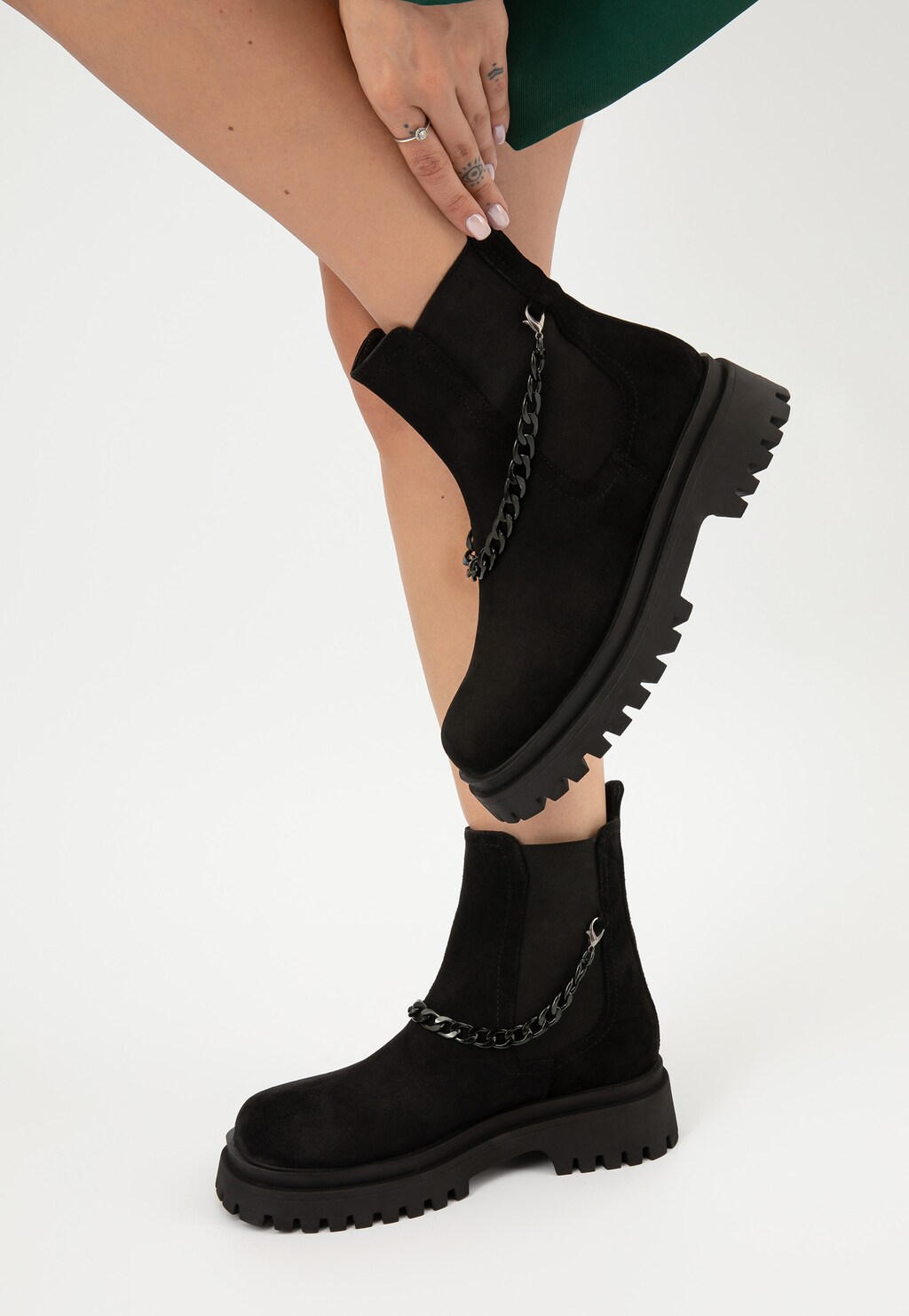 Czarne sztyblety Wojas 55183-61 z dwoiny welurowej prezentowane na nodze modelki, z charakterystycznym odczepianym łańcuchem ozdobnym i grubą podeszwą.