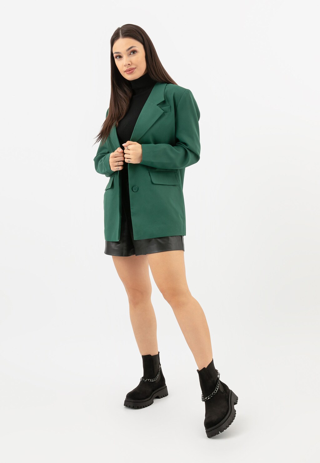 Kobieta w zielonym marynarce i czarnej spódnicy prezentuje czarne sztyblety Wojas model 55183-61 z odczepianym łańcuchem, wykonane z dwoiny welurowej.