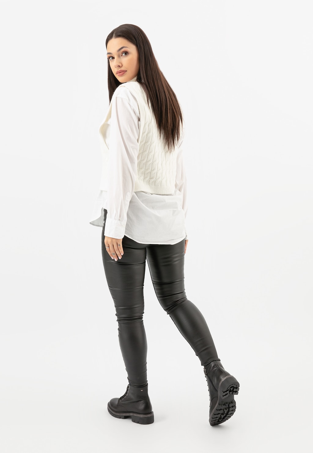 Modelka w białej bluzce i czarnych spodniach prezentuje trzewiki damskie Wojas model 64098-51 - czarne skórzane buty sięgające nad kostkę z charakterystyczną podeszwą.