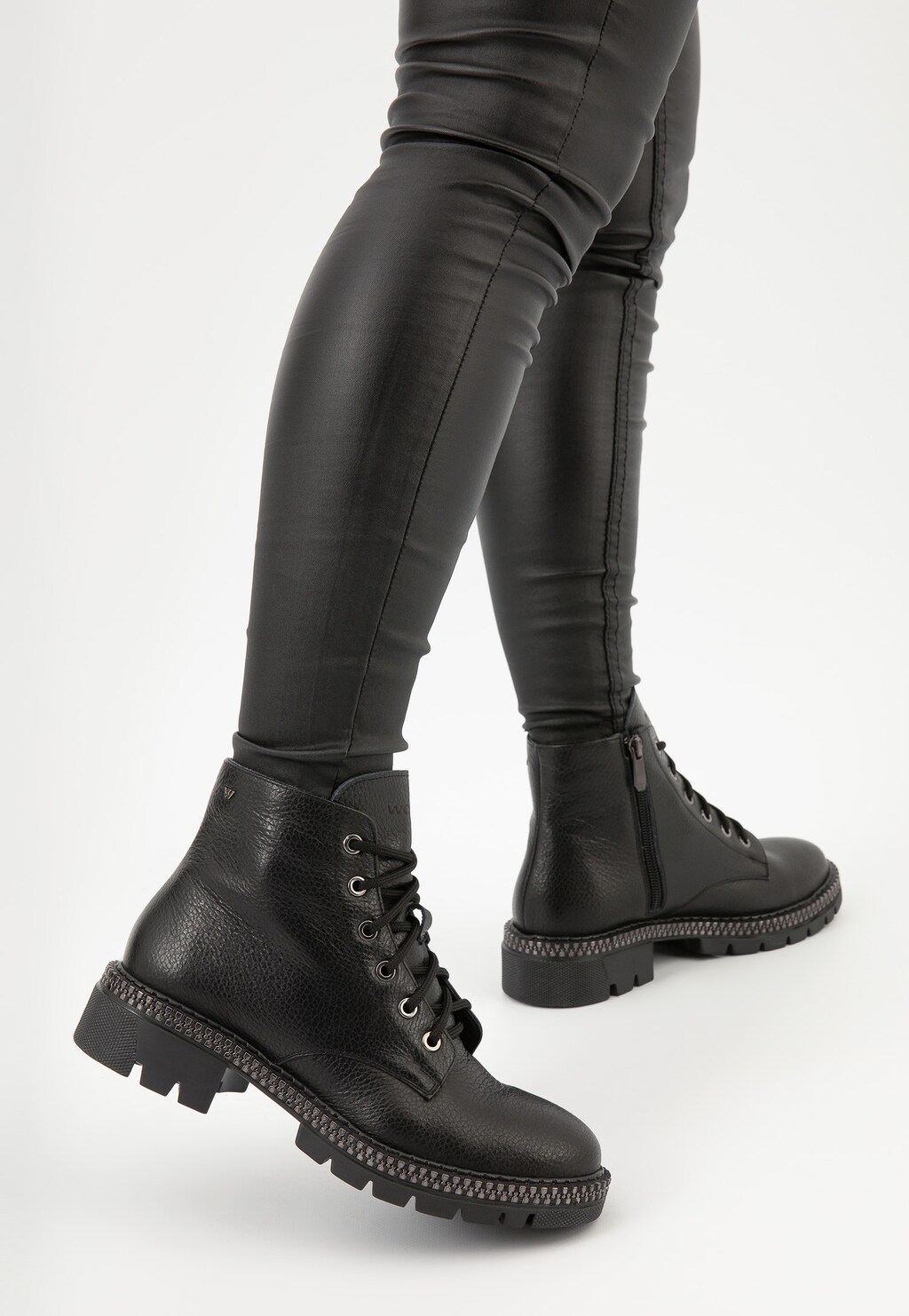 Czarne skórzane trzewiki damskie Wojas model 64098-51 nad kostkę z grubą podeszwą, widoczne na nodze w ciemnych spodniach, ukazane z profilu.