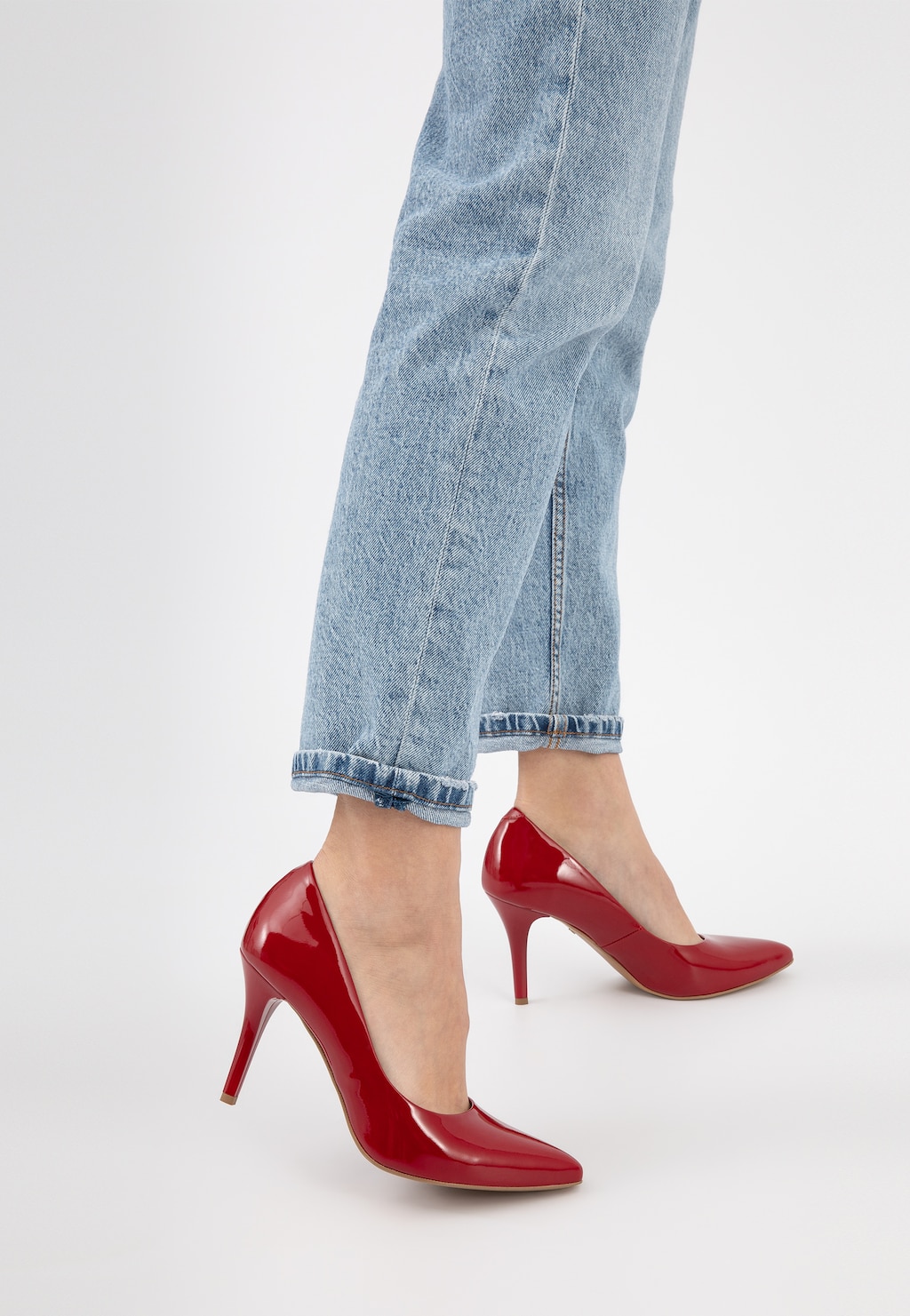 Eleganckie czerwone czółenka Wojas model 9275-35 z lakierowanej skóry na szpilce, prezentowane na nogach w jasnych jeansach, widok z boku.