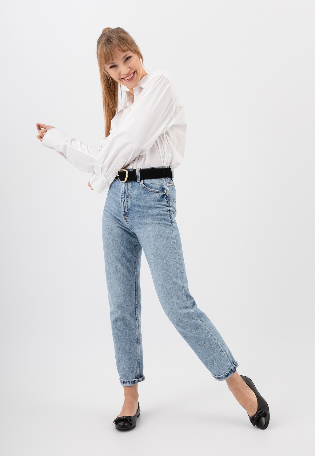 Modelka w białej koszuli i jeansach prezentuje czarne baleriny Wojas ze skóry licowej model 44007-51, pokazując elegancki i casualowy styl noszenia tego obuwia.