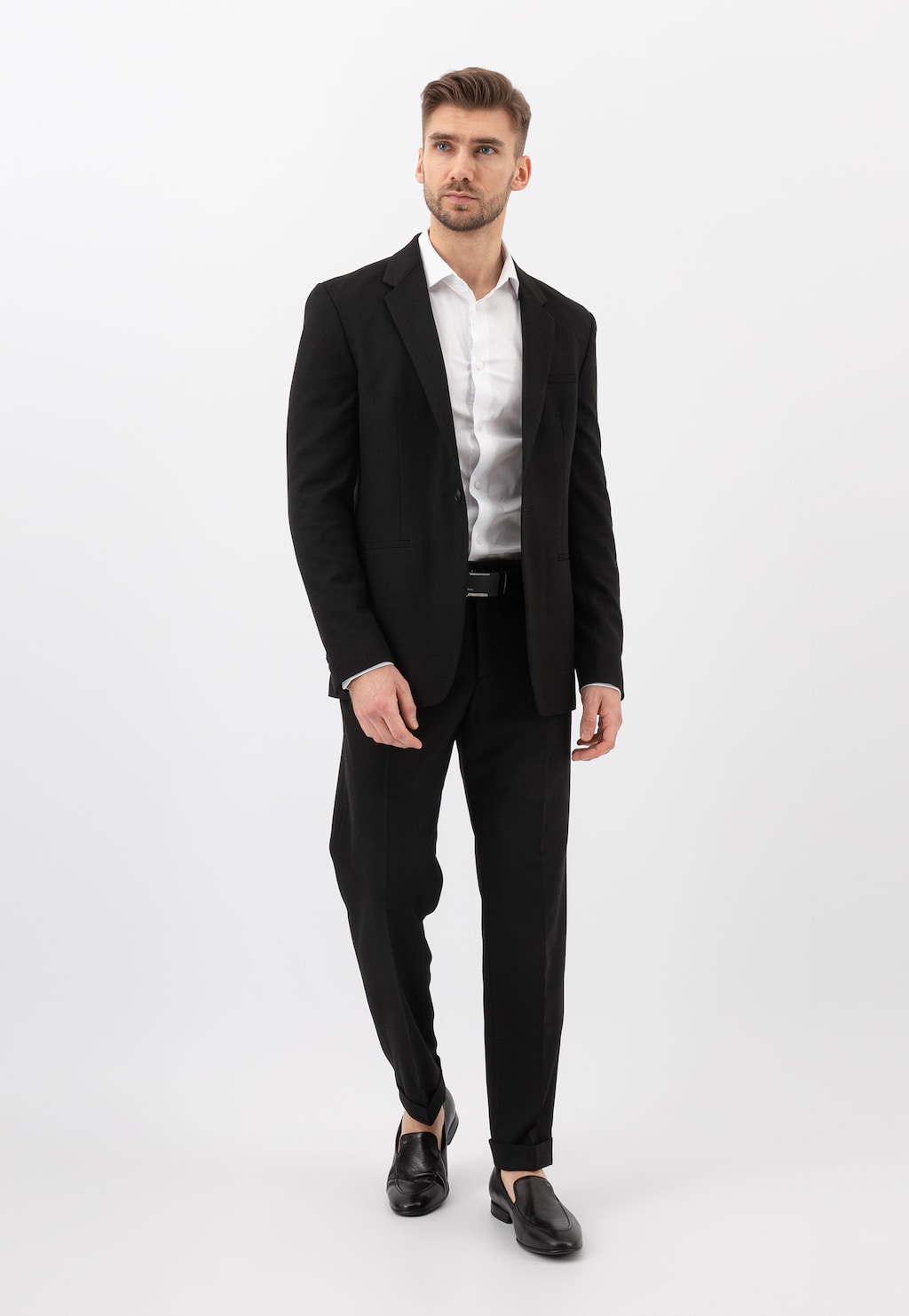 Elegancki mężczyzna w czarnym garniturze i białej koszuli, noszący czarne wsuwane loafersy męskie Wojas model 10004-51, ukazany w pełnej stylizacji biznesowej.