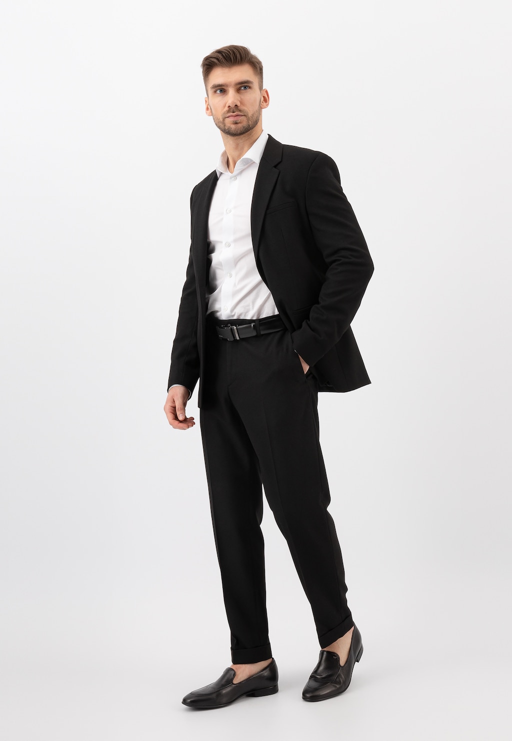 Elegancki mężczyzna w czarnym garniturze i białej koszuli prezentuje czarne loafersy Wojas model 10004-51 apron toe, idealne do formalnych stylizacji biznesowych.
