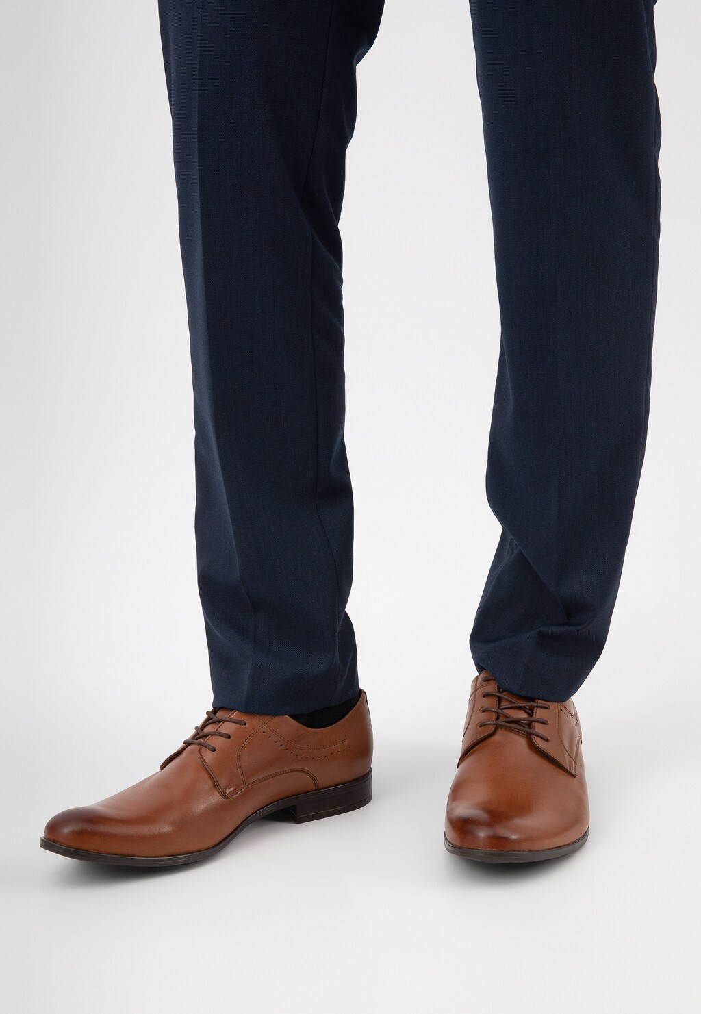 Eleganckie brązowe skórzane półbuty męskie Wojas model 10037-52 ze sznurowaniem, widoczne na nogach w granatowych spodniach, idealne do stylizacji biznesowych.
