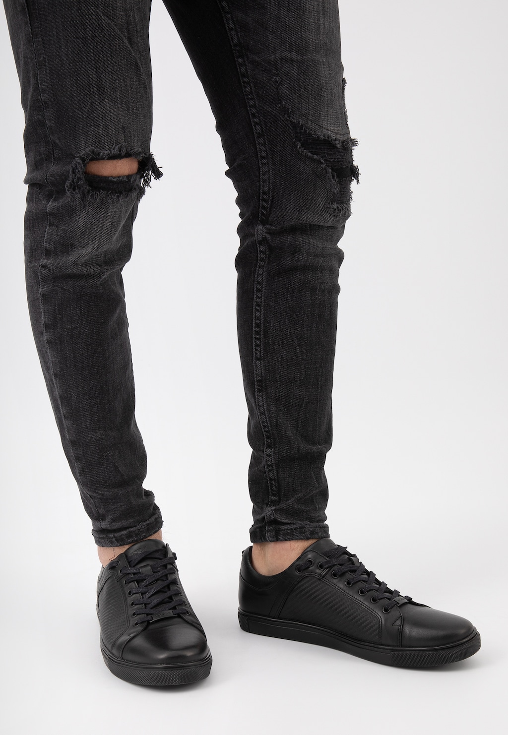 Czarne półbuty męskie Wojas model 10035-51 z tłoczoną wstawką na nodze w podartych dżinsach, widok z boku pokazujący elegancki, sportowy charakter obuwia.