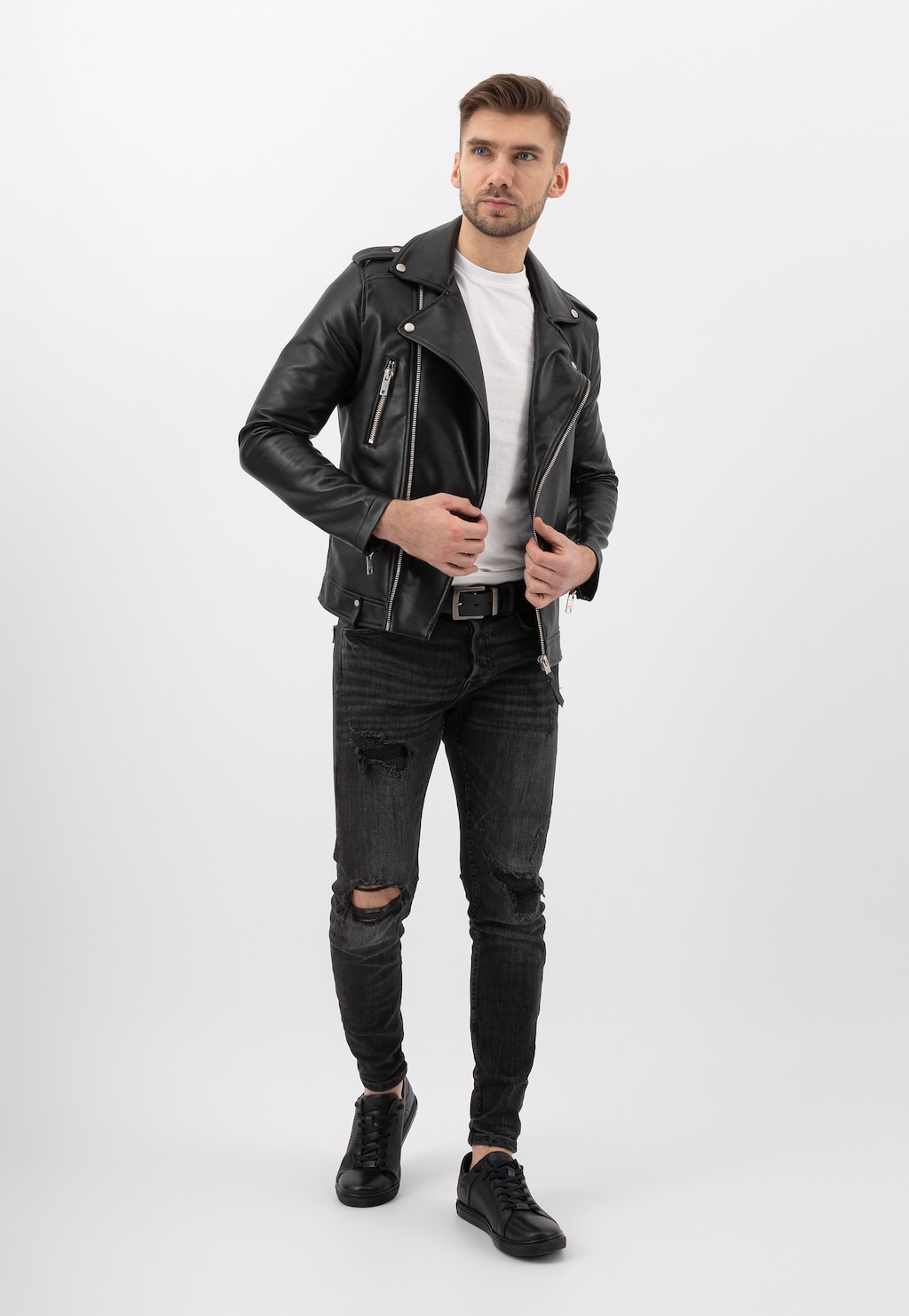 Mężczyzna w czarnej skórzanej kurtce i podartych jeansach, prezentujący czarne półbuty męskie Wojas model 10035-51 z tłoczoną wstawką.