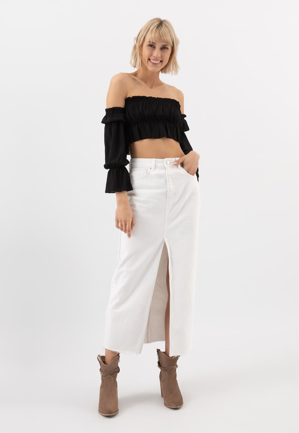 Kobieta w czarnej bluzce typu crop top i białej spódnicy, prezentująca beżowe botki damskie Wojas model 55200-64 z ozdobą wokół cholewki na obcasie.